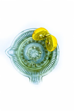 Blue colored glass juicer isolated on white along with some lemon juice extracted in it.の写真素材