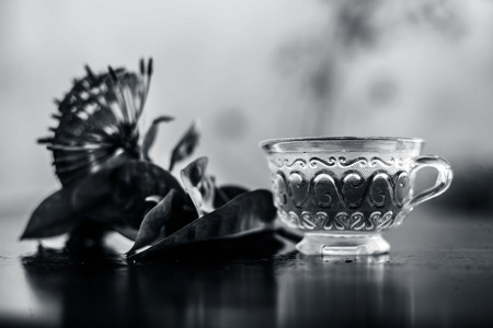 Close up of red colored pentas flower or Egyptian Star Flower or jasmine on wooden surface with its extracted beneficial detoxifying tea in a glass cup.の写真素材