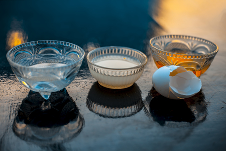 Hair growth remedy on wooden surface in a glass bowl consisting of whole eggs and coconut oil or nariyal oil or Cocos nucifera oil in different containers.の写真素材