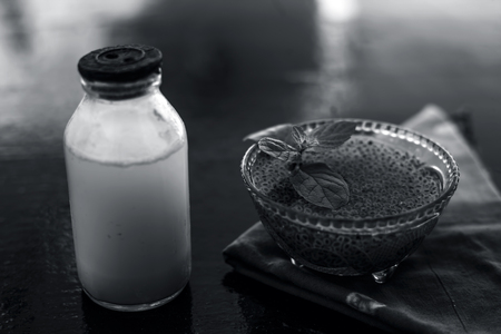 Best home remedy to cure acidity or constipation on wooden surface consisting of sabja seeds or sweet basil seeds or basil seeds well mixed with raw milk.の写真素材
