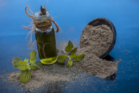 Ayurvedic herb brahmi or Waterhyssop with its essence  in a small transparent glass bottle along with its powder on wooden surface.の写真素材