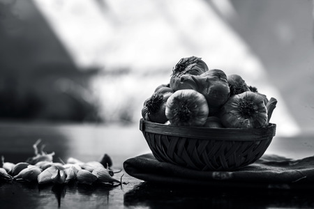 Raw organic garlic bulbs or lasun or Allium sativum in a hamper or basket on wooden surface.の写真素材