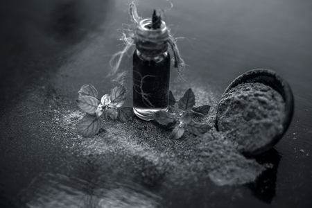 Ayurvedic herb brahmi or Waterhyssop oil in a small transparent glass bottle along with its powder on wooden surface.の写真素材