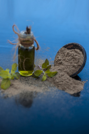 Ayurvedic herb brahmi or Waterhyssop oil in a small transparent glass bottle along with its powder on wooden surface.の写真素材