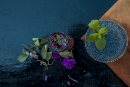 Close up of ingredients of popular Indian and Asian sherbat i.e. Gulab ka sherbat or rose milk on wooden surface which are soaked bail seeds and rose concentration or essence.の写真素材