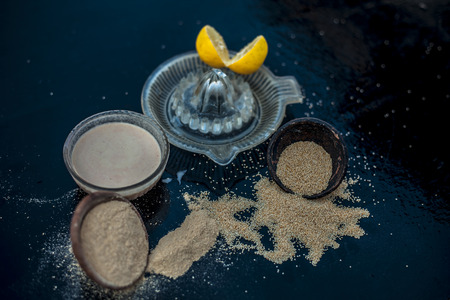 Key ingredients to make poppy seeds cake with lemon juice or muffins or dough nuts on wooden surface i.e. Poppy seeds and its powder and some lemon juice in glass juicer.の写真素材