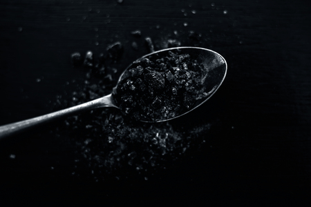 Raw organic rock salt or sendha namak or kala namak in a golden spoon on wooden surface.の写真素材
