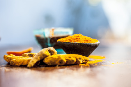 Tamarind or imli or amli in a clay bowl along with its roasted seeds on wooden surface with turmeric...