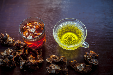 Raw organic amaltas or golden shower tree fruit on wooden surface with its extracted pulp in a glass along with water and green tea in a glass cup.Used for the treatment of worms in intestine.の写真素材