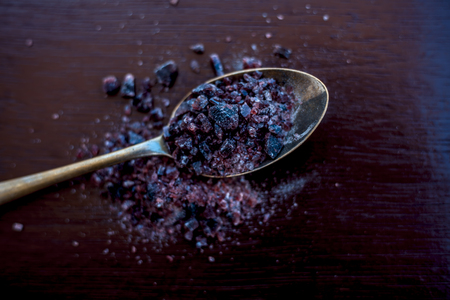 Raw organic rock salt or sendha namak or kala namak in a golden spoon on wooden surface.の写真素材