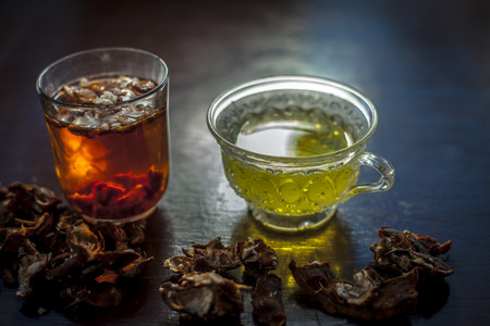 Raw organic amaltas or golden shower tree fruit on wooden surface with its extracted pulp in a glass along with water and green tea in a glass cup.Used for the treatment of worms in intestine.の写真素材