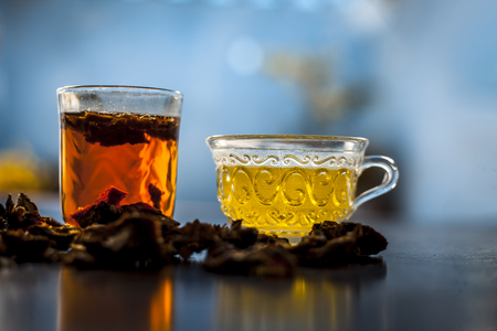 Raw organic amaltas or golden shower tree fruit on wooden surface with its extracted pulp in a glass along with water and green tea in a glass cup.Used for the treatment of worms in intestine.の写真素材