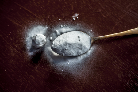Raw baking soda or Sodium bicarbonate in a golden colored brass spoon on brown colored wooden surface.の写真素材