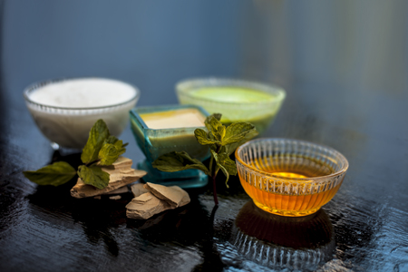 Best face pack or ubtan to remove excess oil from skin on wooden surface consisting of mentha leaves or mint leaves along with fuller's earth or bleaching clay and curd with honey.の写真素材