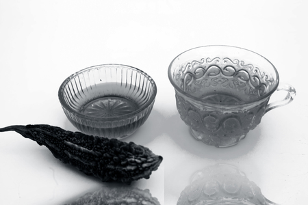 Popular detoxifying herbal tea isolated on white i.e. Bitter melon or Bitter cucumber tea isolated along with honey and its ingredients with their reflection also.の写真素材