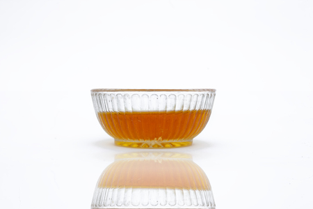 Raw organic honey or nectar in a transparent glass bowl along with its reflection isolated on white.の写真素材