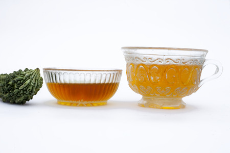 Popular detoxifying herbal tea isolated on white i.e. Bitter melon or Bitter cucumber tea isolated along with honey and its ingredients.の写真素材