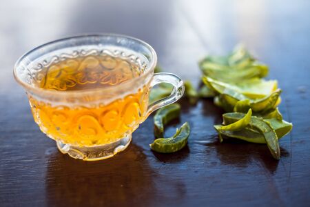 Hot herbal ayurvedic aloe vera tea on wooden surface in  transparent glass cup with entire ingredients with it.Used to build immnue system, To Lower cholesterol levels and many more.の写真素材