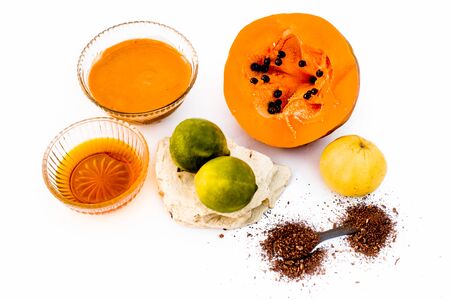 Papaya face mask isolated on white i.e. Papaya along with honey,lemon juice,sandalwood powder, and fuller's earth powder well mixed in a glass bowl and all the ingredients present on the surface.の写真素材