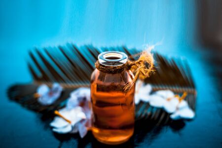 Rosemary concentration or essence in a glass bottle on wooden surface along with its flowers and some leaves.の写真素材