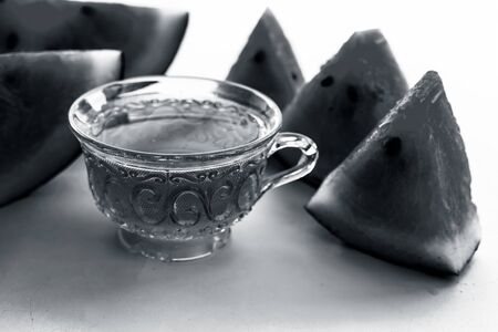 Detoxifying Watermelon seed's tea in a transparent glass cup along with watermelon pieces in triangle shape isolated on white.の写真素材