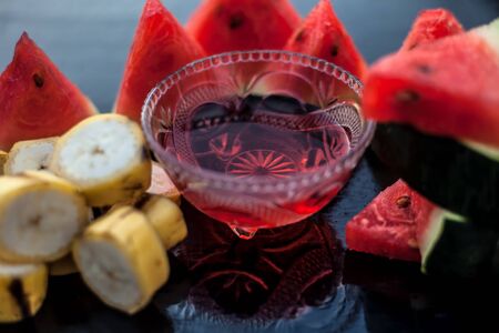 Watermelon face mask or face pack on wooden surface in a glass bowl along with watermelon pieces cut in triangle shape consisting of watermelon and banana.Used for instant natural glow.の写真素材