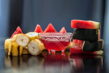 Watermelon face mask or face pack on wooden surface in a glass bowl along with watermelon pieces cut in triangle shape consisting of watermelon and banana.Used for instant natural glow.の写真素材