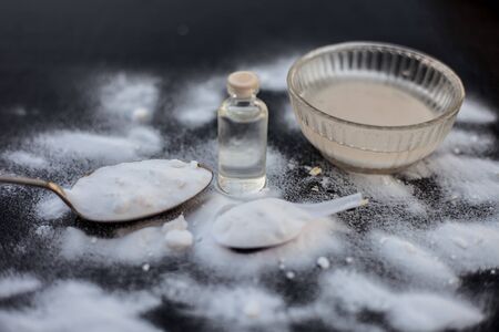 Face mask or face pack of baking soda in a glass bowl on wooden surface along with powder and some coconut oil in a transparent glass bottle. Used for rashes. Horizontal shot.の写真素材