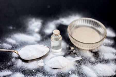 Face mask or face pack of baking soda in a glass bowl on wooden surface along with powder and some coconut oil in a transparent glass bottle. Used for rashes. Horizontal shot.の写真素材