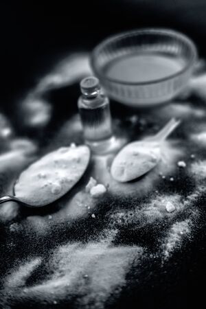 Face mask or face pack of baking soda in a glass bowl on wooden surface along with powder and some coconut oil in a transparent glass bottle. Used for rashes. Vertical shot along with top shot.の写真素材