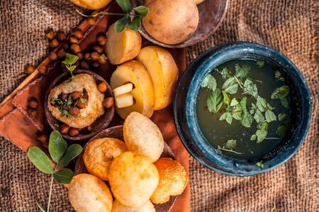 Famous Indian & Asian street food dish i.e. Panipuri snack in a clay bowl along with its flavored...