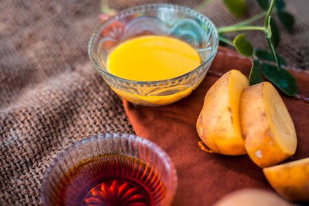 Potato juice's face pack or face mask in a glass bowl on jute bag's surface consisting of potato juice and honey.Used for skin whitening purpose along with entire ingredients.Horizontal low angle.の写真素材