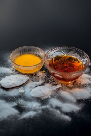 Baking soda face mask in a glass bowl on wooden surface along with baking soda powder and honey for...