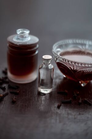 Clove face mask for prevention against acne and pimples on wooden surface in a glass bowl along with clove oil and some coconut oil.の写真素材