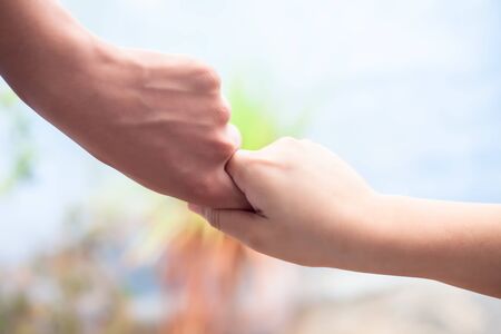 Hand of female child holding the hand of matured man, Shot with blurred background. Concept of Fatherâs day. Men helping the female hand to overcome conquer obstacles and fears. Horizontal shot.の写真素材