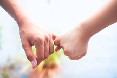 Female childâ€™s hand holding the hand of elder male shot with bokeh background and horizontal....