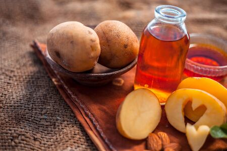 Glowing face mask of potato juice in a glass bowl on brown colored surface along with some Potato juice,honey and almond oil.Horizontal shot.To eliminate skin rashes, remove impurities,etc.の写真素材