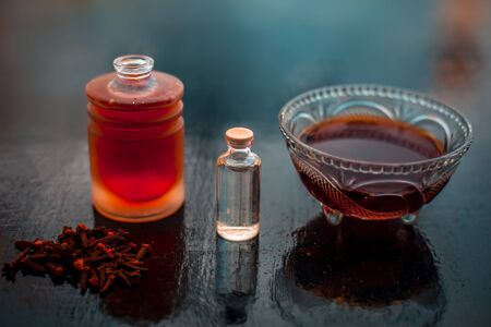 Clove face mask for prevention against acne and pimples on wooden surface in a glass bowl along with...