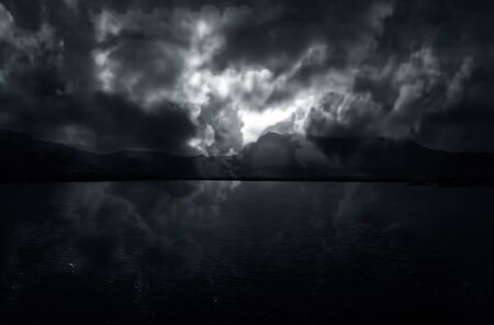Dramatic manipulated sunrise shot with mountains,clouds and water (lake).の写真素材