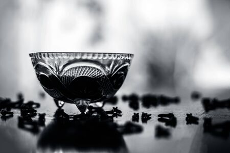Ready to use apply face mask of clove and its oil in  at transparent glass bowl on wooden surface  along with some cloves spread on the surface.の写真素材