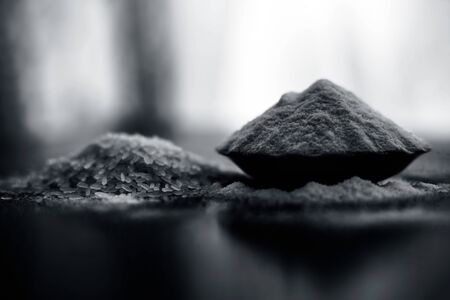 Close up of rice flour and raw whole rice grain in a glass plate on wooden surface along with blurred background.の写真素材