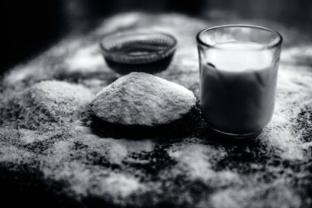 Face mask for flawless skin on wooden surface consisting of rice flour,corn flour,honey,milk, in a glass bowl and entire raw ingredients present on the surface.の写真素材