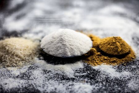 Face mask for glowing skin on wooden surface consisting of rice flour & dried orange peel powder in a glass bowl along with some rice flour spread on the surface for greater effect.Horizontal shot.の写真素材