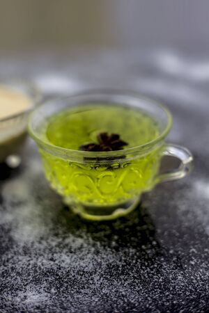 Rice flour and rice grain on wooden surface along with some green tea in a transparent glass cup and a star anise in it.Face mask for the treatment for smoother skin.の写真素材