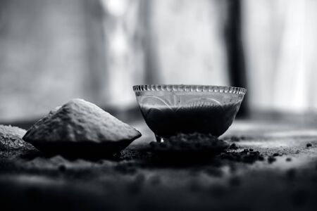 Hair growth remedy of rice flour water and fenugreek/coriander/parsley seeds powder on wooden surface and its paste in a glass bowl with some rice flour spread on the surface.の写真素材
