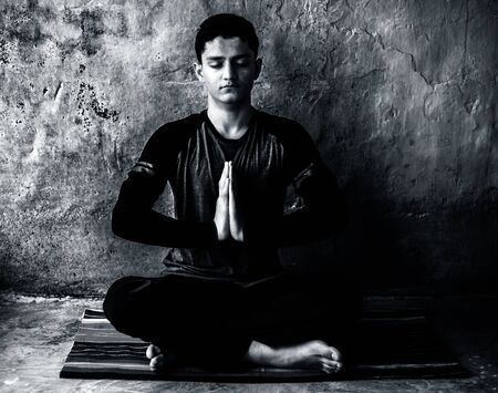 Easy Pose or Sukhasana performed by a young man doing on the colorful mat by wearing black attire.