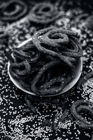 Famous Indian snack in a glass plate on the wooden surface along with raw sesame seeds or til spread...