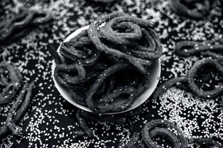 Famous Indian snack in a glass plate on the wooden surface along with raw sesame seeds or til spread...