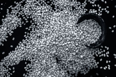 Unskinned split mung dal or moong dal in a black colored clay bowl on the black wooden surface used...