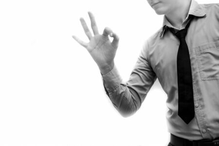 Ok/alright/perfect/ okay sign by too young businessman wearing blue colored shit and black colored tie isolated on white.の写真素材